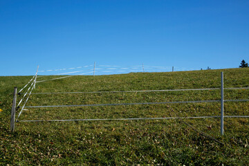 pasture meadow with electronic keeper against blue sky