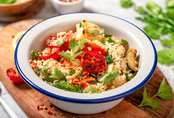 Salad of couscous and fried vegetables. Arab or Middle Eastern cuisine. Spicy couscous with cilantro, green onions, lemon and grilled tomatoes, zucchini and pepper. Vegan food.