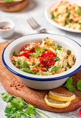 Salad of couscous and fried vegetables. Arab or Middle Eastern cuisine. Spicy couscous with cilantro, green onions, lemon and grilled tomatoes, zucchini and pepper. Vegan food.