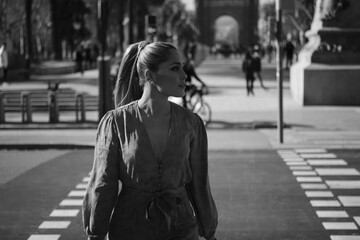 Portrait of young gorgeous woman confidently crossing the road along street. Black and white