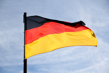 flag of the federal republic of Germany freely flutters in the wind against a blue sky, , concept of tourism, economy, politics, emigration, business