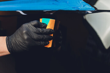 Car detailing - Man applies nano protective coating to the car. Selective focus.