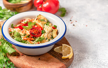 Couscous and fried vegetables salad, free space for text. Arab or Middle Eastern cuisine. Spicy couscous with cilantro, green onions, lemon and grilled tomatoes, zucchini and pepper. Vegan food.