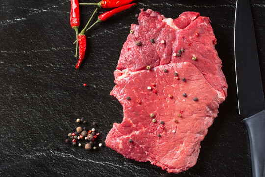 Raw beaf meat. Fresh steaks on slate board on black background. Top view