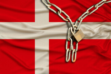 iron chain and castle on the silk national flag of Denmark with beautiful folds, the concept of a...