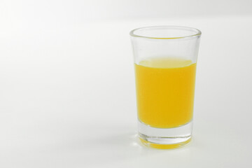 Shot of yellow in a glass. Glass of yellow alcohol. 