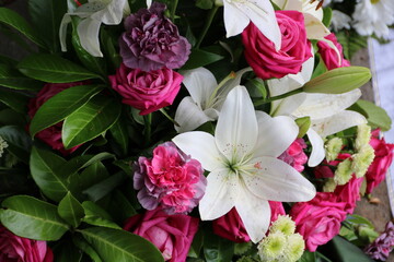 Weiße Lilien und rosa Nelken und Rosen nach Beerdigung auf dem Friedhof