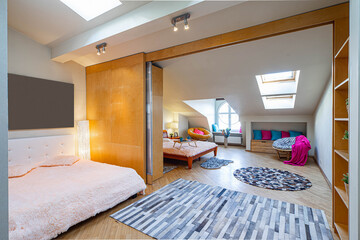 Modern interior of bedroomwith two beds in apartment. Roof windows. Zoning with sliding door. Wooden furniture.