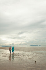 Fototapeta na wymiar Lonely beach seascape with silhouette of two Muslim women walking at sunrise along the beach.