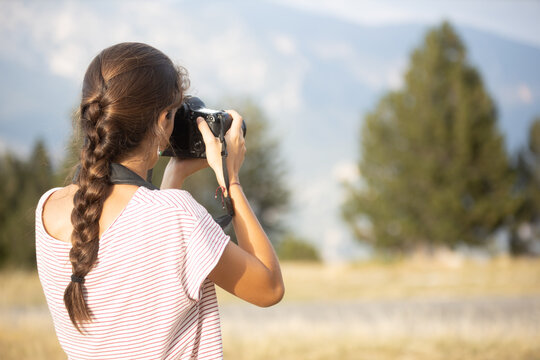 teenage girl seen from behind taking photos in the forest