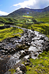 Paysage pittoresque et coloré avec un ruisseau coulant à travers champ et nature verdoyante dans le Connemara sauvage d'Irlande.