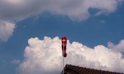 Windsack auf einem Gebaeude mit Wolken