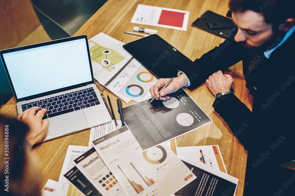Poster cropped image of male partners sitting at desktop with graphic diagrams for analysis company income,