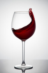 A splash of red wine in a glass on a white background