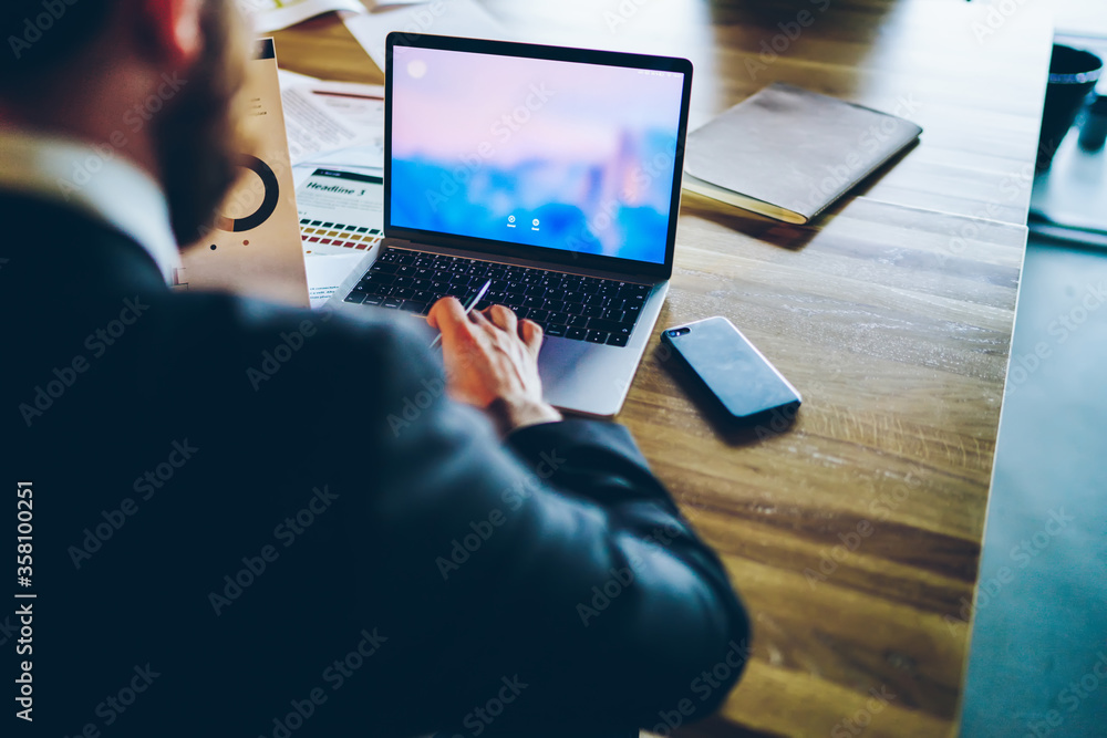 Poster back view of male entrepreneur using application on laptop computer for browse information on web pa