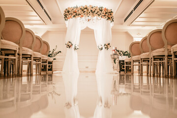 The wedding arch is decorated with flowers.. Interior of a luxury hotel