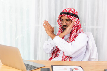 Arabian businessman feeling disappoint and say no while talking with his business partner by video conference on notebook in his office