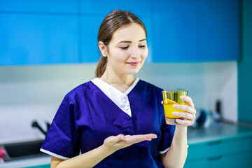 Woman standing holding a glass of juice after cleaning the house.