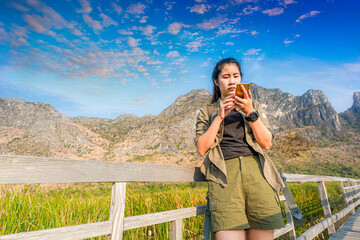 Asian hikers carry heavy backpacking on a small Pavilion outdoor hiking path on a wooden bridge in a swamp with meadows with a blue mountain background. Khao Sam Roi Yot National Park