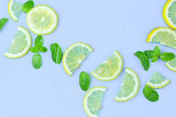 Juicy lemon slices and mint leaves on blue table top view. Flat lay style.