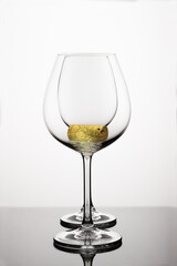 Two empty wineglasses on diffision with yellow cork inside is on a table in a white background. abstract composition with reflection, advertizing shot for restaurant, winemaking