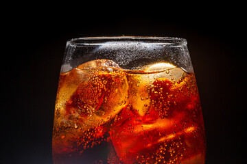 A glass of cola beverage with a salt. On a black background
