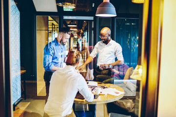 Smiling multiethnic colleagues working at table in office