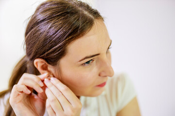 Fototapeta premium Woman putting in earrings on her ears