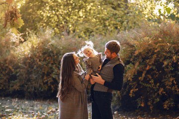 Family in a autumn park. Woman in a brown dress. Cute little girl with parents