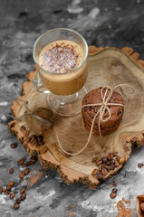 Obraz na płótnie Canvas a cookie with pieces of chocolate tied with a string lies on a wooden board and next to a cup of latte