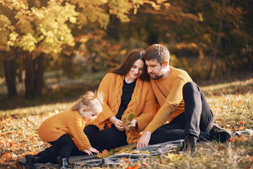 Family in a autumn park. Woman in a yellow sweater. Cute little girl with parents