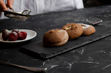 chocolate chip cookies on a table with strawberries and icing sugar
