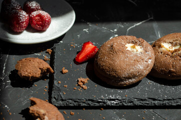 chocolate chip cookies on a table with strawberries and icing sugar