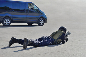 special forces soldier lying on the ground aiming from an assault rifle near the car