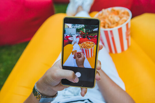 woman taking picture of snacks for social networks on her phone at open air cinema