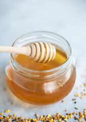 Honey and honey spoon on a light background. Sweet honey in the jar, place for text.
