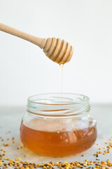 Honey and honey spoon on a light background. Sweet honey in the jar, place for text.
