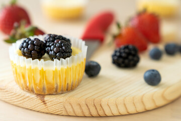 Blackberry mini cheesecake and decorated with strawberry and blueberry in the background