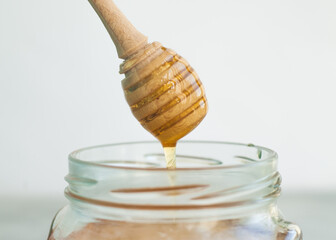Honey and honey spoon on a light background. Sweet honey in the jar, place for text.
