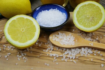 Close up of isolated sliced yellow citrus fruits, blue bowl and wooden spoon with coarse sea salt...