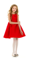 Beautiful girl in a red fashionable dress stands and smiles at the camera