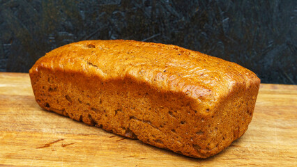Gluten-free whole grain rye bread on the kitchen cutting board on black background. Healthy food concept..