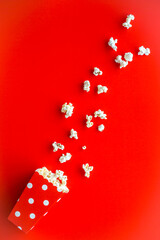 Popcorn in paper cup on red desk top view