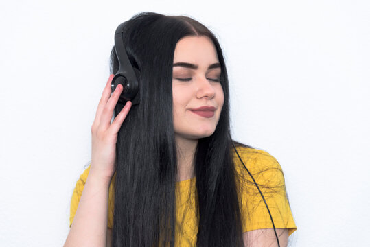 Joy and music. Young teenager enoy and listening the music in his room. White backgroung and yellow T-shirt.