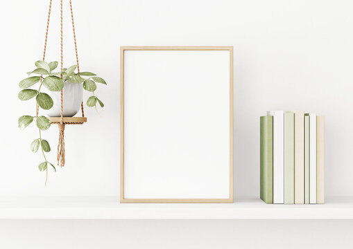 Interior poster mockup with vertical wooden frame on the shelf with green plant in hanging pot, books and trendy decoration on empty white wall background. A4, A3 size. 3D rendering, illustration.