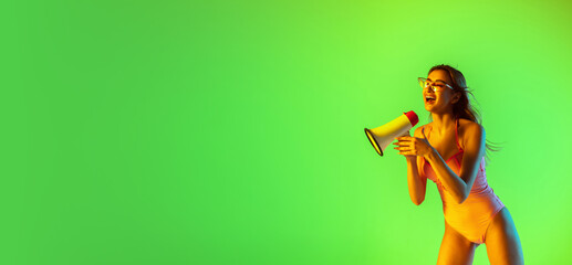 Shouting. Beautiful young girl' portrait on gradient studio background in neon. Woman in fashionable bodysuit with megaphone. Facial expression, summer, weekend, beauty, resort, sale concept. Flyer.