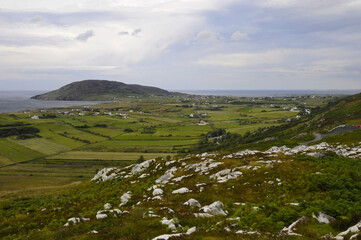 Fototapeta na wymiar Vue panoramique sur la côte nord irlandaise, ses champs, ses collines, ses rochers et son ciel nuageux, depuis une route au sommet d'un col.