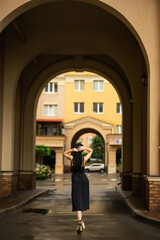 girl in a black dress stands in the arch of the house