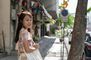 Asian beautiful young woman shoulder bag and looking at the camera while walking on the street.