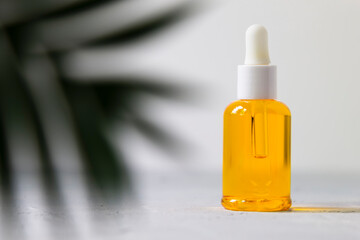 Dropper glass bottle oil mock up. osmetic pipette on gray background with tropical leaves shadows